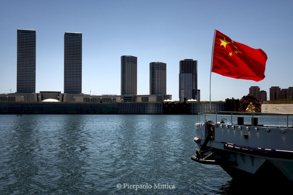 The Chinese flag flies in front of the new and empty skyscrapers of Ordos