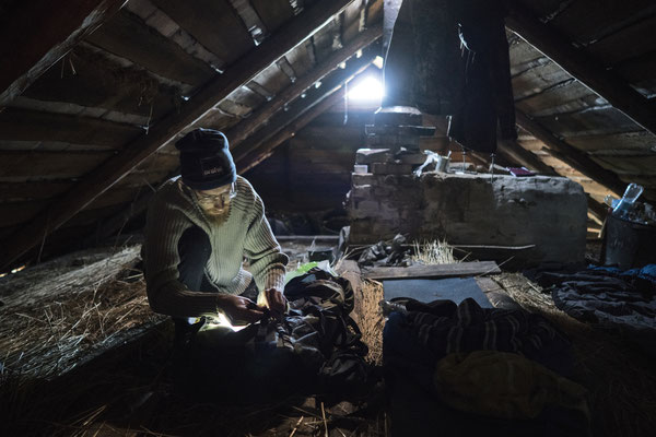 Sasha preparing for the night in the abandoned village of Rudnya Veresnya. Stalkers usually sleep in the garret, to stay safe from wild animals now abundant in the zone: wolves, boars, bears and mooses – mices and ticks keep them good company, anyway