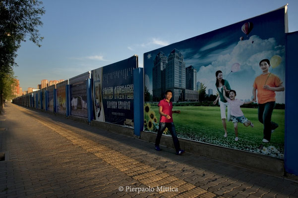  A pedestrian passes in front of billboards that promise a happy life in new and never completed buildings