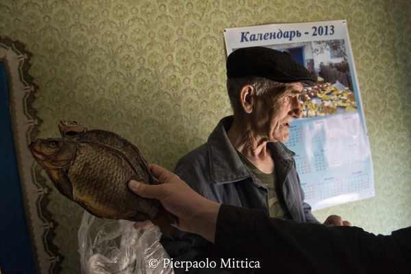 Ivan con un pesce secco preparato per affrontare l’inverno, villaggio di Kupovate, zona di esclusione di Chernobyl