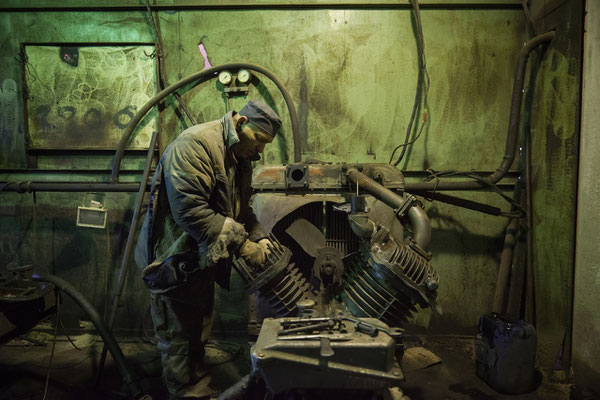 Pasha while repairing an engine that is used to force ventilation in the radioactive scrap metal recycling facilities. Chernobyl Exclusion Zone.