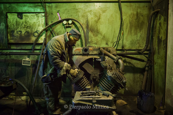 Pavel fixing the engine of the ventilation system inside the warehouse for the recycling of the radioactive metals