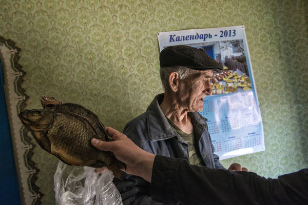 Ivan Ilchinko and a smoked fish as a winter stock pile. Ivan died on 2019. Kupovate, Chernobyl Exclusion Zone.