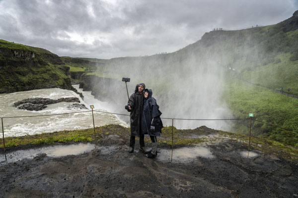 Iceland. Tourists pose for photos in front of the Gulfoss Waterfall, one of the most famous waterfalls in south western Iceland and a favourite tourist destination.