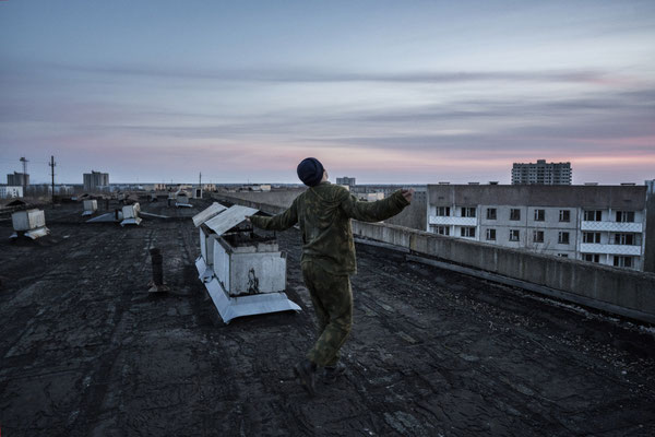 A stalker dancing at sunset on the roof of a building of the ghost town of Pripyat.
