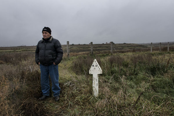 Gosman Kabirov, antinuclear activist, next to a radiation sign along the Techa River, evacuated and contaminated village of Muslyumovo