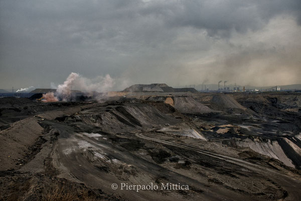 A surface mine, marked by the explosions of the extraction activities