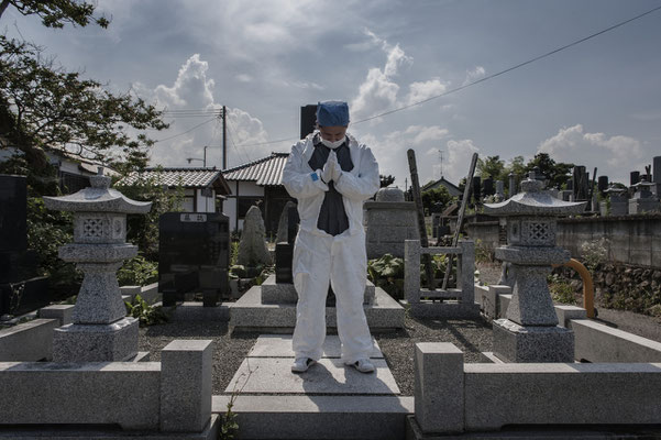 Mister Matsumoto, Yakuza member and Tepco contractor is praying on his family grave, Fukushima "No-Go Zone", Japan.