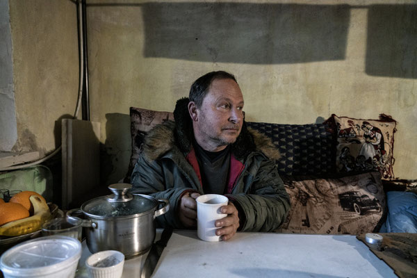  Oleksandr while warming himself with a cup of tea in his house, he has living here from the beginning of the war, without electricity, water and Heating. Horenka.