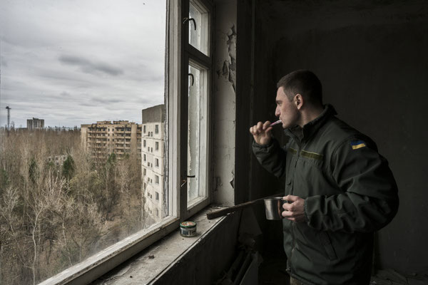 Maxim brushing his teeth in Jimmy’s apartment, looking at the landscape of the ghost town of Pripyat.