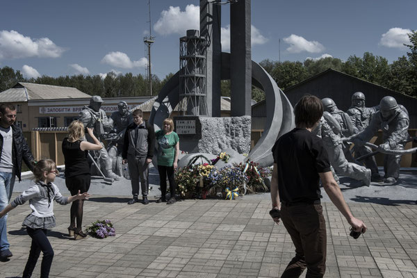 Former residents of the area with their families taking souvenir photos in front of the memorial to the Chernobyl firefighters. Chernobyl city.