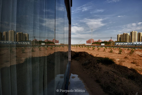 The new district of Kangbashi reflected in the window of a never opened real estate agency