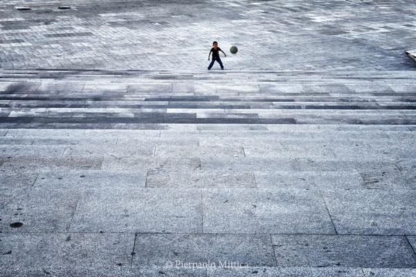 A child playing football in an empty square