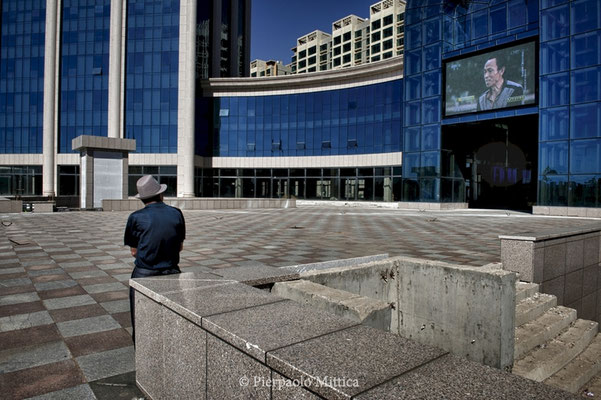  An unfinished shopping center with a big TV screening all day