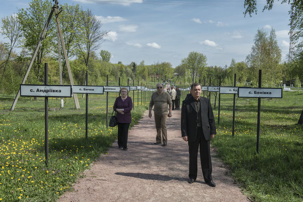 Former inhabitants strolling in the main square of the city of Chernobyl where the monument was erected in memory of the towns abandoned due to the accident. Chernobyl city.