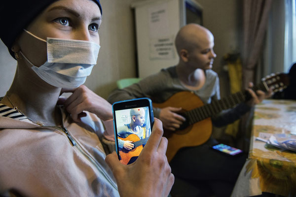 Olia, 14 years old is affected by an osteosarcoma. Here she is filming her friend Ania playing guitar. Ania suffers from a thyroid and ovaius cancer. family home, Kiev.