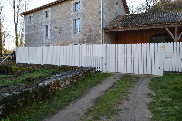 Clôture avec pillasses en béton et éléments bois.