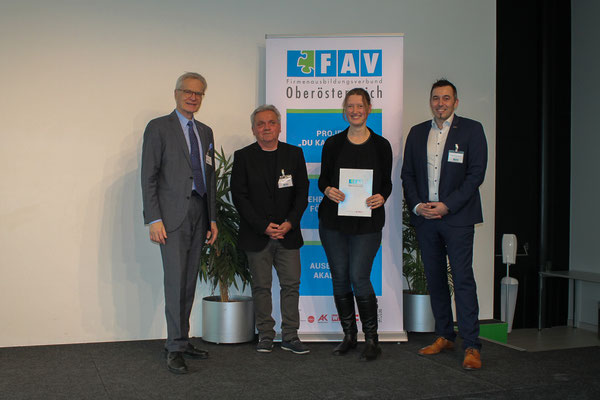 Gruppenbild mit Absolventin, Urkunde und Projektleitung auf der Bühne