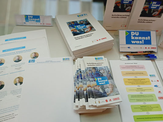 Infomaterialien wie Flyer, Kugelschreiber und Ablaufpläne am Tisch ausgelegt