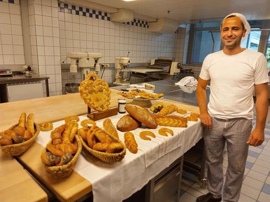 Absolvent zeigt stolz seine Backwaren neben dem Buffet