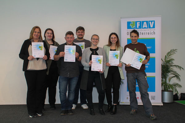 Gruppenfoto mit Zertifikaten vor FAV OÖ-Roll-Up