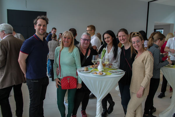 Lockeres Gruppenbild mit Absolvent:innen und Gästen im Foyer