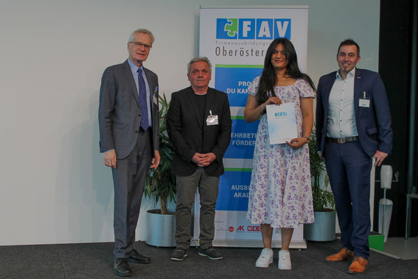 Lächelndes Abschlussfoto mit Gratulanten vor dem FAV OÖ Rollup