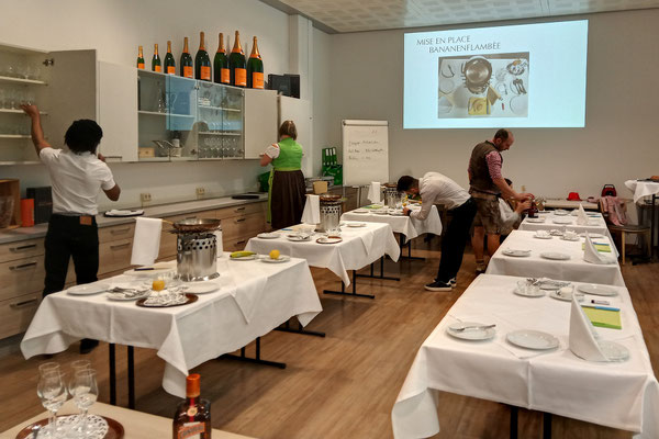 Angehende Restaurantfachkräfte trainieren das fachgerechte Decken eines Tisches