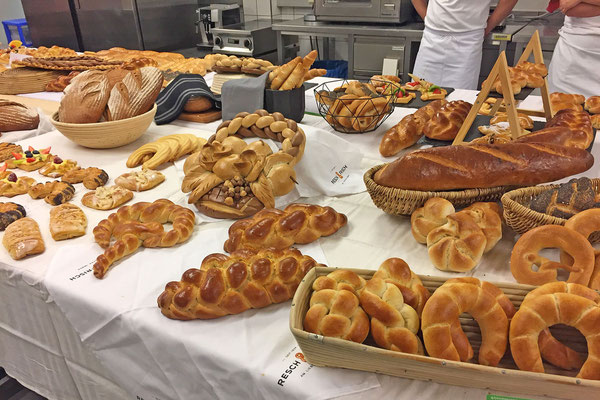 Brot- und Gebäcksortiment auf einem großen Präsentationstisch in der Backküche