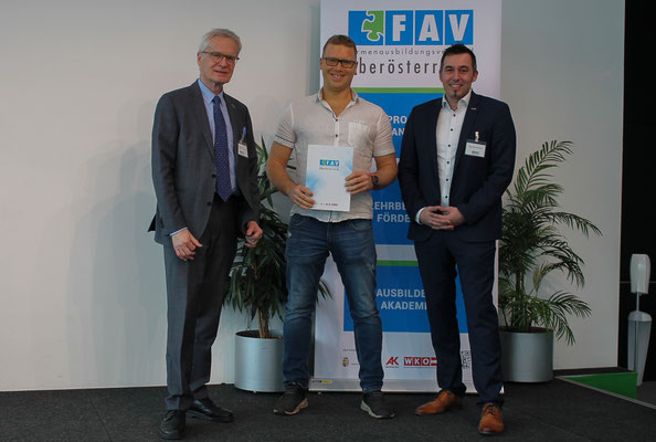 Absolvent posiert mit Gratulanten nach Übergabe