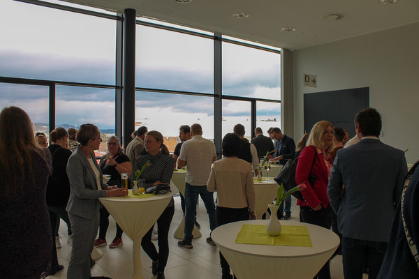 Stehtische im Raum mit vielen Teilnehmenden beim Netzwerken