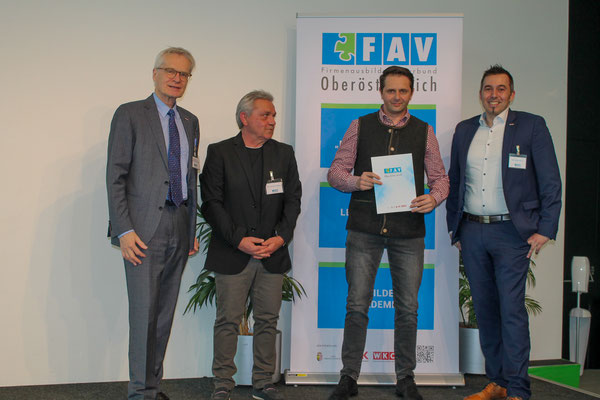 Absolvent hält stolz die Urkunde bei Gruppenfoto