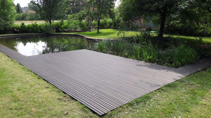 Schwimmteich mit edlen Bambus-Terrassendielen in dunkelbraunem Espresso-Ton. Die pflegeleichten, wetterfesten Bambusdielen sorgen für eine moderne und nachhaltige Gestaltung im Außenbereich. 