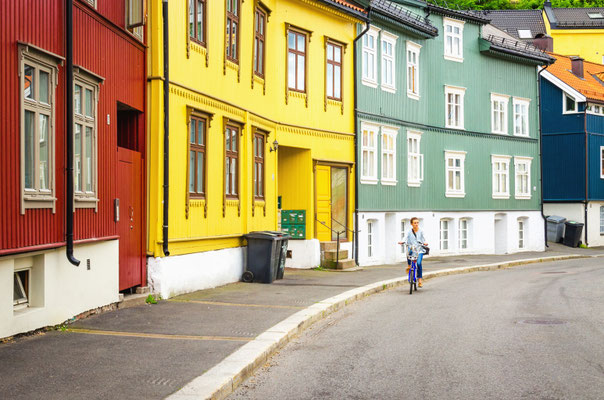 Colorful wooden house architecture and a young tourist on a bike in Oslo, Scandinavia Copyright Anna Jedynak