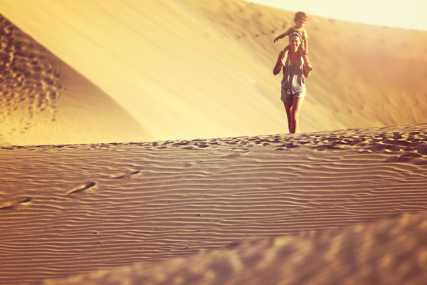 Gran Canaria - European Best Destinations - Fit mother with son walking in a desert in Gran Canaria, Maspalomas on the sunset Copyright SASHAandLENKA