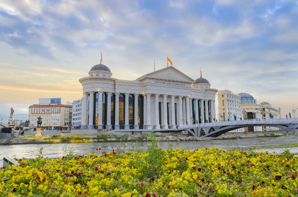 Amazing sunrise of archaeological museum of Macedonia with river Vardar, bright colorful sky and spring flowers foreground Copyright  zefart