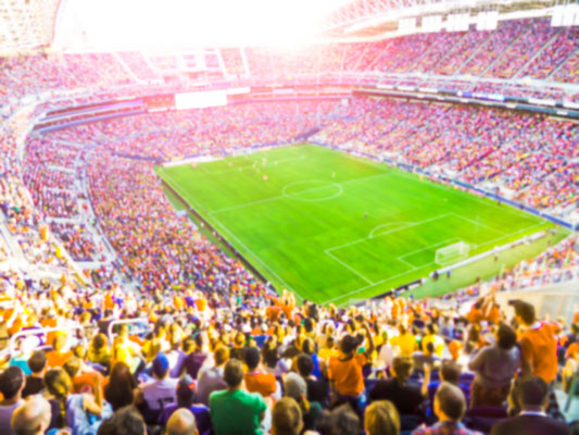 Football- soccer fans cheer their team and celebrate goal in full stadium with open air with bright lighting beam -blurred. Copyright Checubus