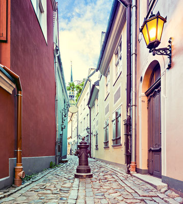 Narrow street in old city of Riga at night. Image toned in vintage warm colors for inspiration of retro style effect Copyright Sergei25