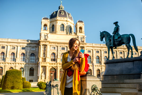 Young female tourist with smart phone on Maria Theresa square near museum of Natural history in Vienna. Copyright Ross Helen