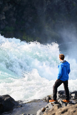 Iceland tourist looking at dramatic river by waterfall Godafoss. Man hiker on travel visiting tourist attractions and landmarks in Icelandic nature on Ring Road, Route 1. Copyright Maridav  - European Best Destinations 