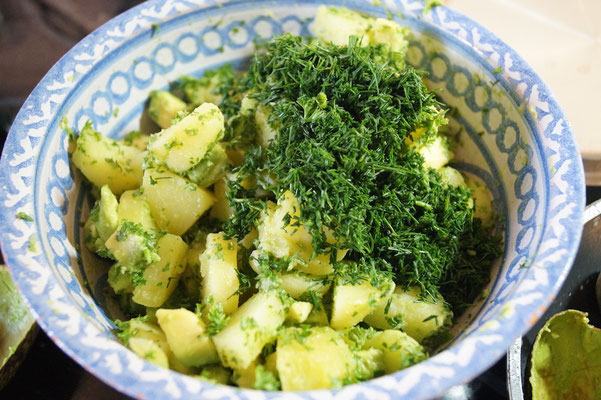 Dill und Petersilie hacken und zu den Kartoffeln geben.