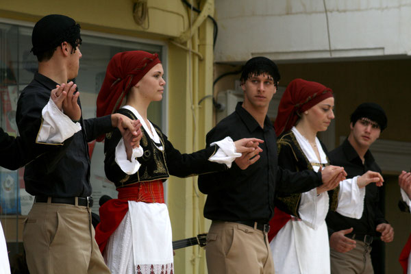 Cretan dancers in traditional clothes are holding hands