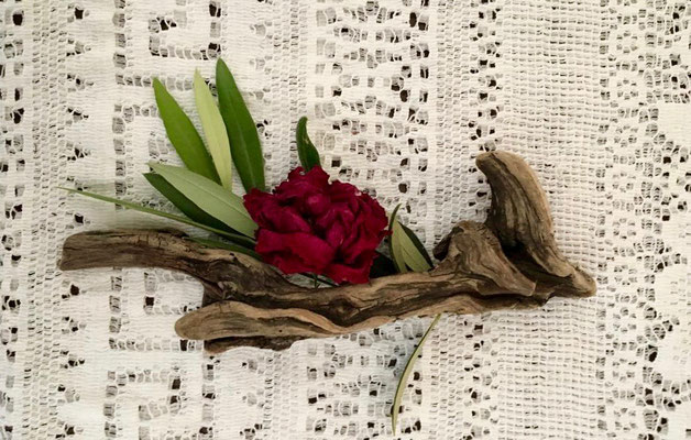 driftwood and roses with olive leaves on a embroidered table cloth