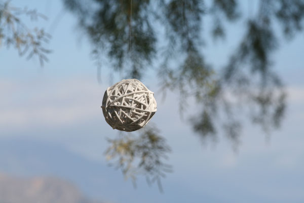weißer Baumschmuck hängt an einem Zweig