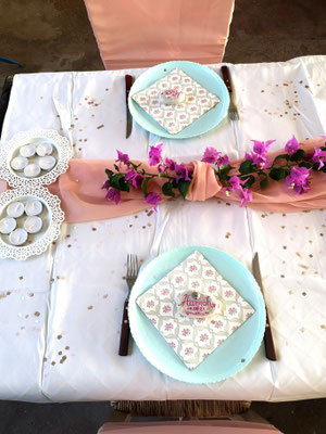 dekorierte Hochzeitstafel mit Tellern und Blumenschmuck aus Bougainvilliablüten