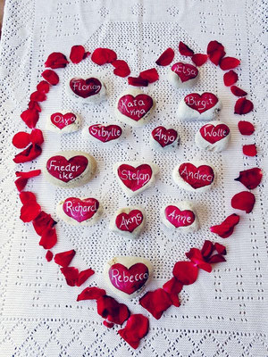 red hearts painted on stones and framed by rosebuds 