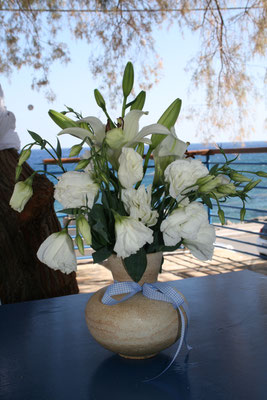 weißer Blumenstrauß in einer Vase mit Blick aufs Meer