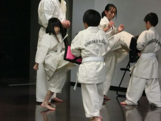 小学生の女子が、キックミットで前蹴りの練習をしている様子