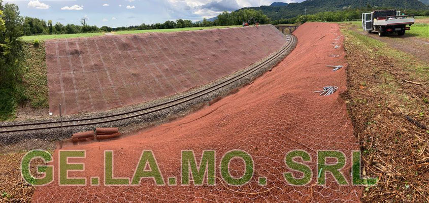 Consolidamento scarpate su linea ferroviaria con tiranti in barre a perdere, reti paramassi accoppiate con tessuti polimerici e pannelli.