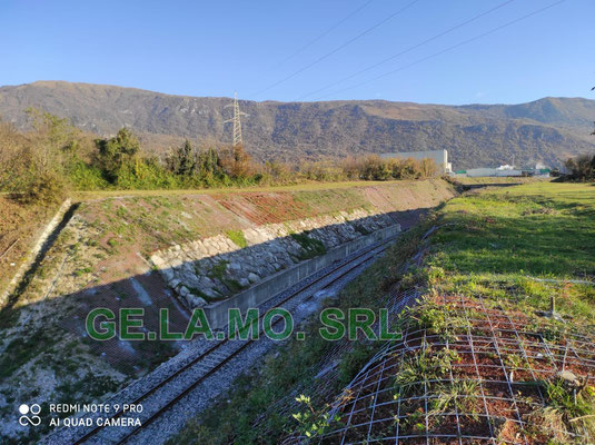 Consolidamento scarpate su linea ferroviaria con tiranti in barre a perdere, reti paramassi accoppiate con tessuti polimerici e pannelli.